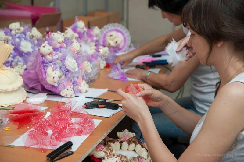 People working together on crafting with colorful materials and decorations on a table.